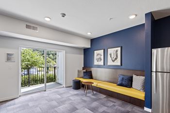 A living room with a yellow couch and a door to a balcony
