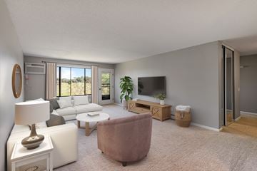 Bloomington apartment for rent - A living room with a brown chair, a white sofa, a white side table with a lamp, a flat screen TV, and a sliding glass door leading to a balcony.