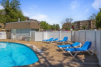 A swimming pool with blue chaise lounge