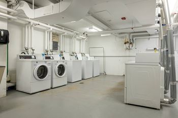 A row of washing machines and dryers in a laundry room