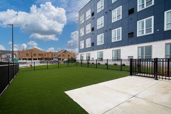 The yard of an apartment building with a green lawn and a fence