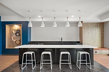 A kitchen with a white counter and black stools.