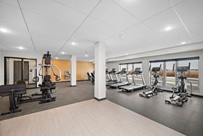 Rosemount apartment for rent - A gym with a variety of equipment including treadmills, stationary bikes, and weight machines at The Landing at Amber Fields Apartments, Rosemount, MN, 55068
