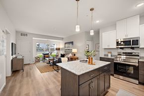 Rosemount apartment for rent - A modern kitchen with dark wood cabinets and a granite countertop at The Landing at Amber Fields Apartments, Rosemount, MN
