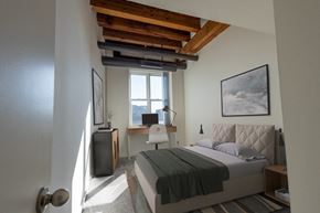 St. Paul apartment for rent - a bedroom with a bed and a desk and a window at Lowertown Commons Apartments, St. Paul, MN, 55101