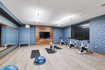 A gym with exercise equipment and a tv on the wall