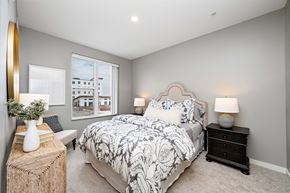 Woodbury apartment for rent - A bedroom with a large bed and a window overlooking a building.