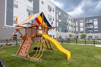 A playground with a swing set and a slide in an apartment building