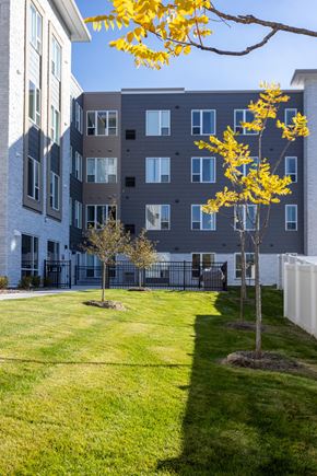 Mahtomedi apartment for rent - a courtyard with grass and trees in front of an apartment building