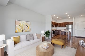 Rochester apartment for rent - A modern living room with a white couch and a yellow accent pillow.