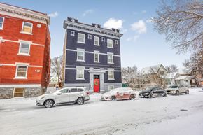 Winnipeg apartment for rent - Cars are parked in front of a blue building with a red door.