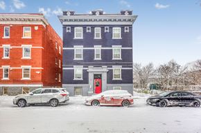 Winnipeg apartment for rent - A red car is parked in front of a blue building.