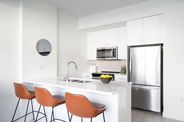 Winnipeg apartment for rent - A modern kitchen with orange chairs and a white counter.