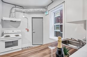 Winnipeg apartment for rent - A kitchen with a stove, a sink, and a bottle of champagne on the counter.