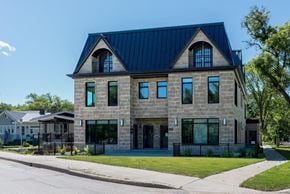 Winnipeg apartment for rent - a stone house with a blue roof and a sidewalk