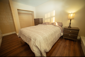 Thompson apartment for rent - A bedroom with a bed, nightstand and lamp.