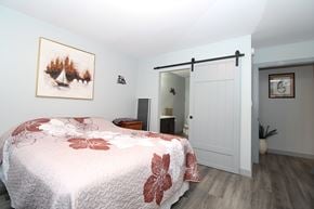 Ile Des Chenes townhouse for rent - A bedroom with a bed covered in a red and white quilt.