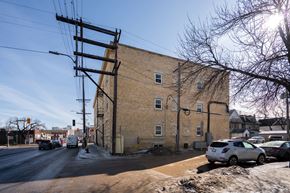 Winnipeg apartment for rent - A street view with a car driving and a building on the side.