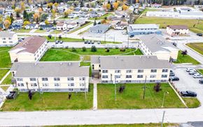 Thompson apartment for rent - A large building complex with a parking lot in front.