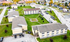 Thompson apartment for rent - A large building complex with a parking lot in front.