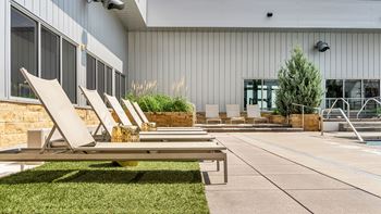 A poolside area with lounge chairs and a building in the background.