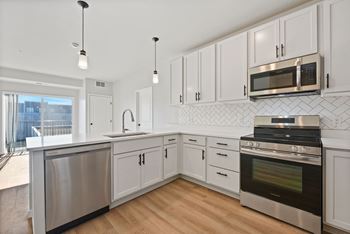 A modern kitchen with white cabinets and stainless steel appliances.