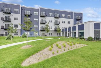A modern apartment complex with a well-maintained lawn in front.
