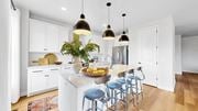 Champlin townhouse for rent - A kitchen with white cabinets and a large island with blue stools.at Field and Grove Townhomes of Champlin, Champlin Minnesota
