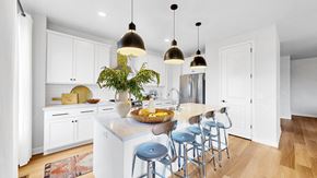 Champlin townhouse for rent - A kitchen with white cabinets and a large island with blue stools.at Field and Grove Townhomes of Champlin, Champlin Minnesota