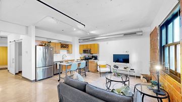 Minneapolis apartment for rent - A modern living room with a grey couch and a kitchen in the background.