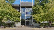 Bloomington apartment for rent - A modern building with a glass facade is surrounded by green trees.
