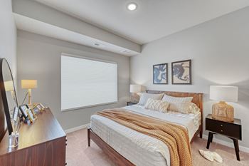 A bedroom with a large bed and a nightstand with a lamp.