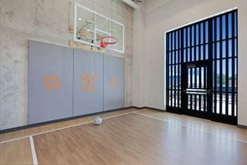 A basketball court with a ball on the floor and a basketball hoop with a net