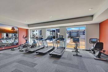 A gym with treadmills, exercise bikes, and a television.