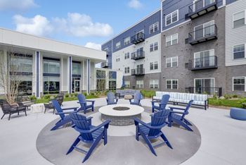 A patio with blue chairs and a fire pit.