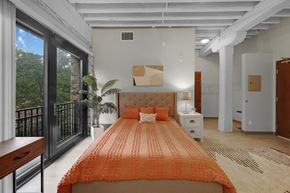 Minneapolis apartment for rent - A bedroom with a large bed and a balcony with a view of trees at The Cameron North Loop, Minneapolis