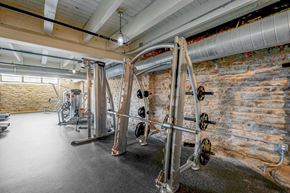 Minneapolis apartment for rent - A gym with a brick wall and a row of exercise machines.