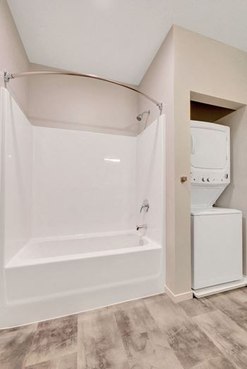 A white bathroom with a tub and a washer and dryer