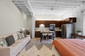 Minneapolis apartment for rent - A modern living room with a white couch and a kitchen area in the background.