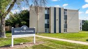 Fridley apartment for rent - A sign for River Park Crossing Apartments stands in front of a building.
