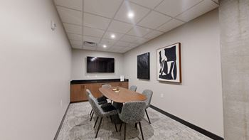 A conference room with a table, chairs, and two framed pictures on the wall.