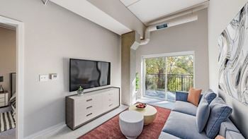 A modern living room with a television, sofas, and a balcony