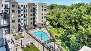 Bloomington apartment for rent - A large apartment complex with a pool and a view of the surrounding greenery.