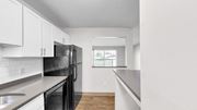 Bloomington apartment for rent - A black fridge in a kitchen with white cabinets and a window.