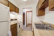 Bloomington apartment for rent - a kitchen with a sink stove and refrigerator and a door to a hallway