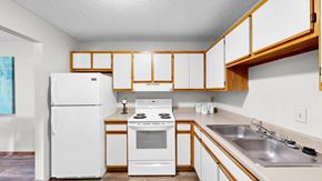 Eagan apartment for rent - A white refrigerator and oven in a kitchen with wooden cabinets.
