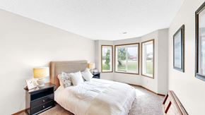Eagan apartment for rent - A bedroom with a large bed and a nightstand with a lamp.