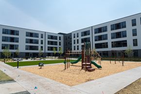Rosemount apartment for rent - A playground with a green slide and sandbox in front of a building.