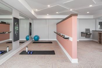 A room with a pink wall and a mirror on the left side.