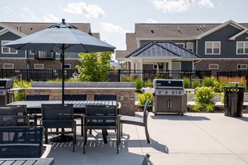 A patio with a table and chairs and an umbrella.